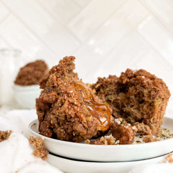 zucchini muffin on a white plate with honey poured on top