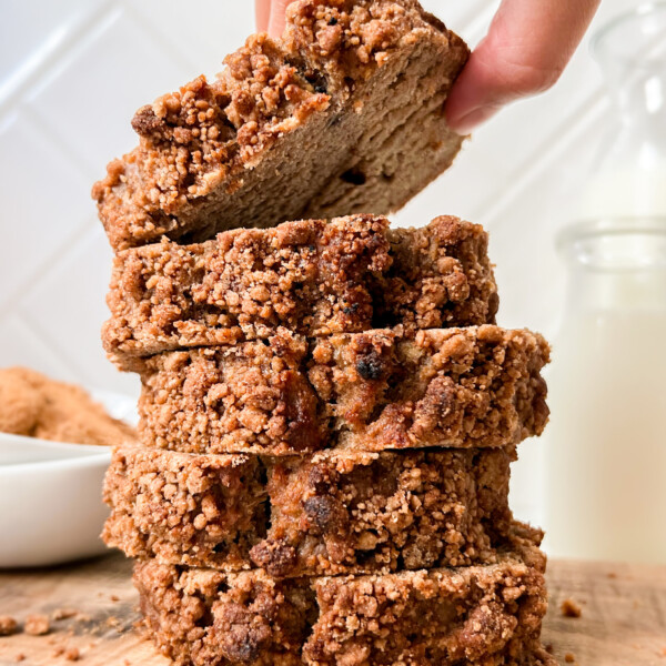 coffee cake slices stacked on a cutting board next to a bottle of milk