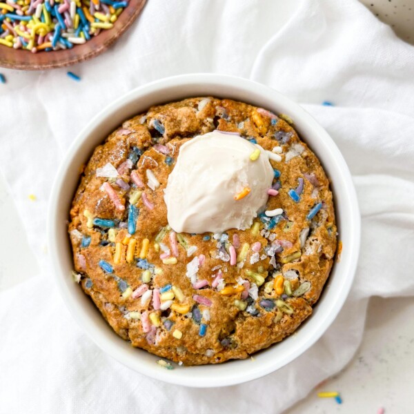 baked oats in a ramekin next to a bowl of sprinkles