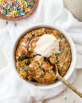 baked oats in a ramekin next to a bowl of sprinkles