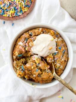 baked oats in a ramekin next to a bowl of sprinkles