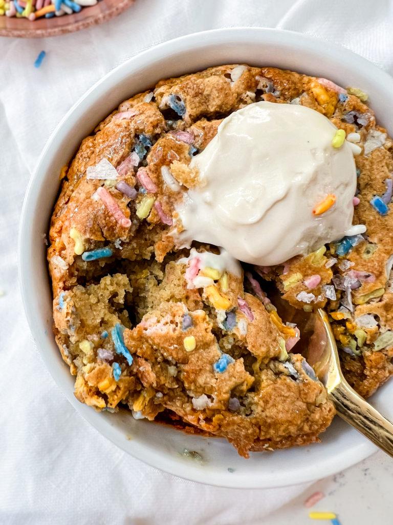 baked oats in a ramekin next to a bowl of sprinkles