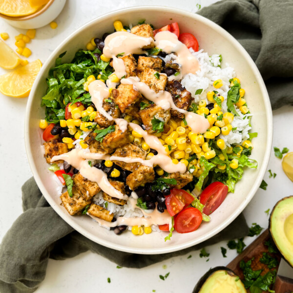 vegan chipotle burrito bowl on a green linen cloth next to lemon wedges and avocado