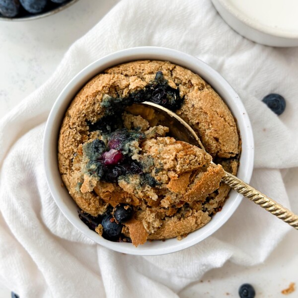 baked oats in a ramekin next to a glass of milk and bowl of berries