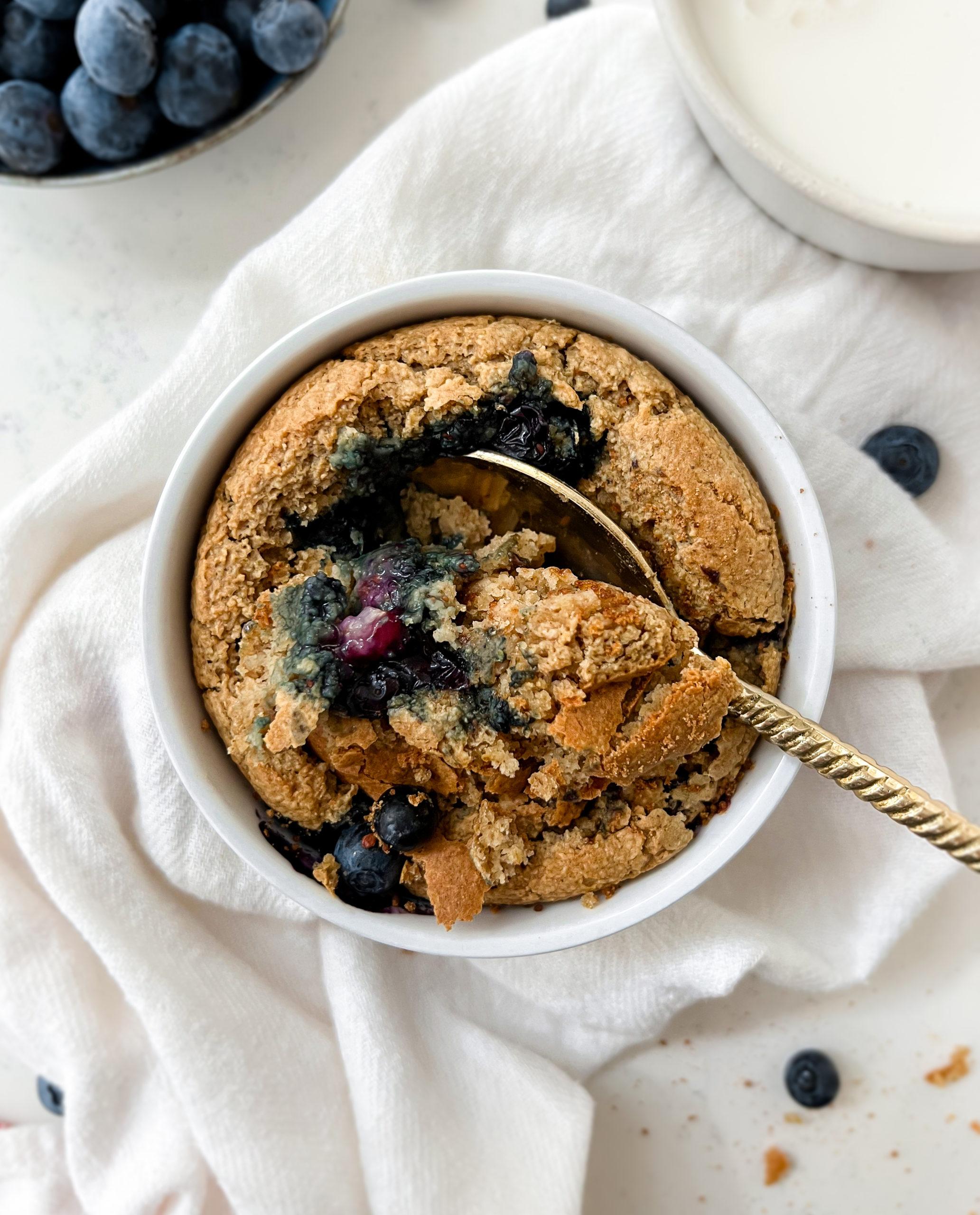 baked oats in a ramekin next to a glass of milk and bowl of berries