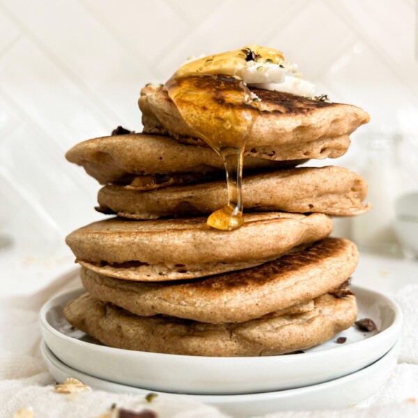 pancakes stack on a white plate with honey on top