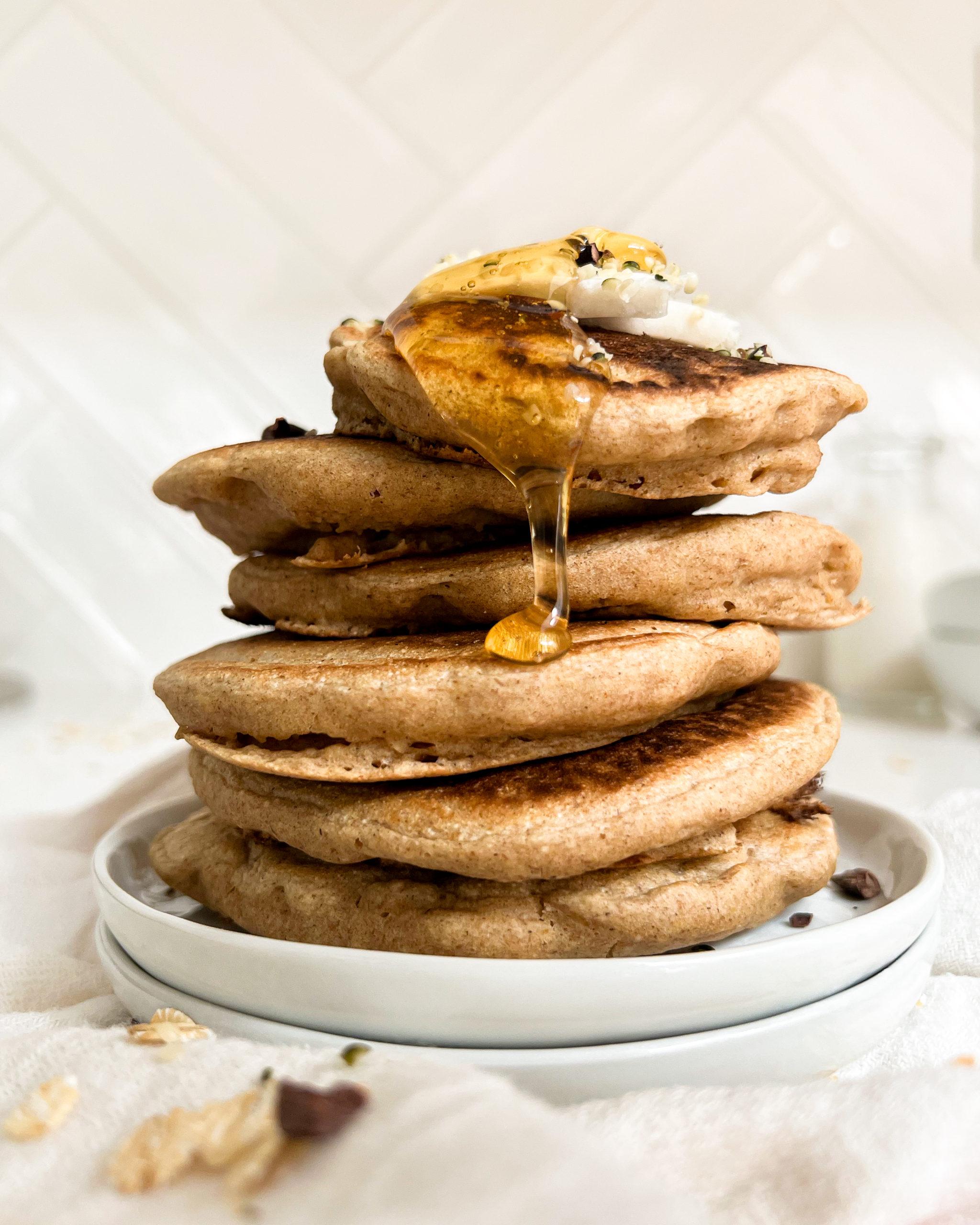 pancakes stack on a white plate with honey on top 