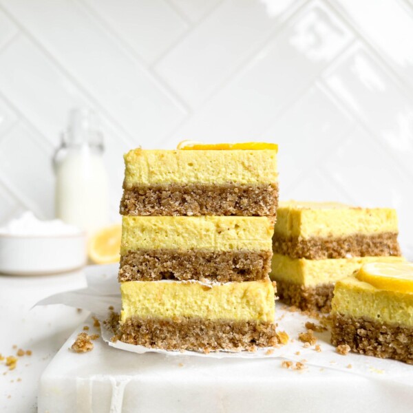 creamy vegan lemon bars stacked on a white cutting board