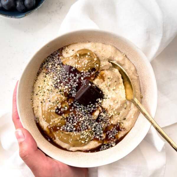 oatmeal in a bowl with a gold spoon next to blueberries