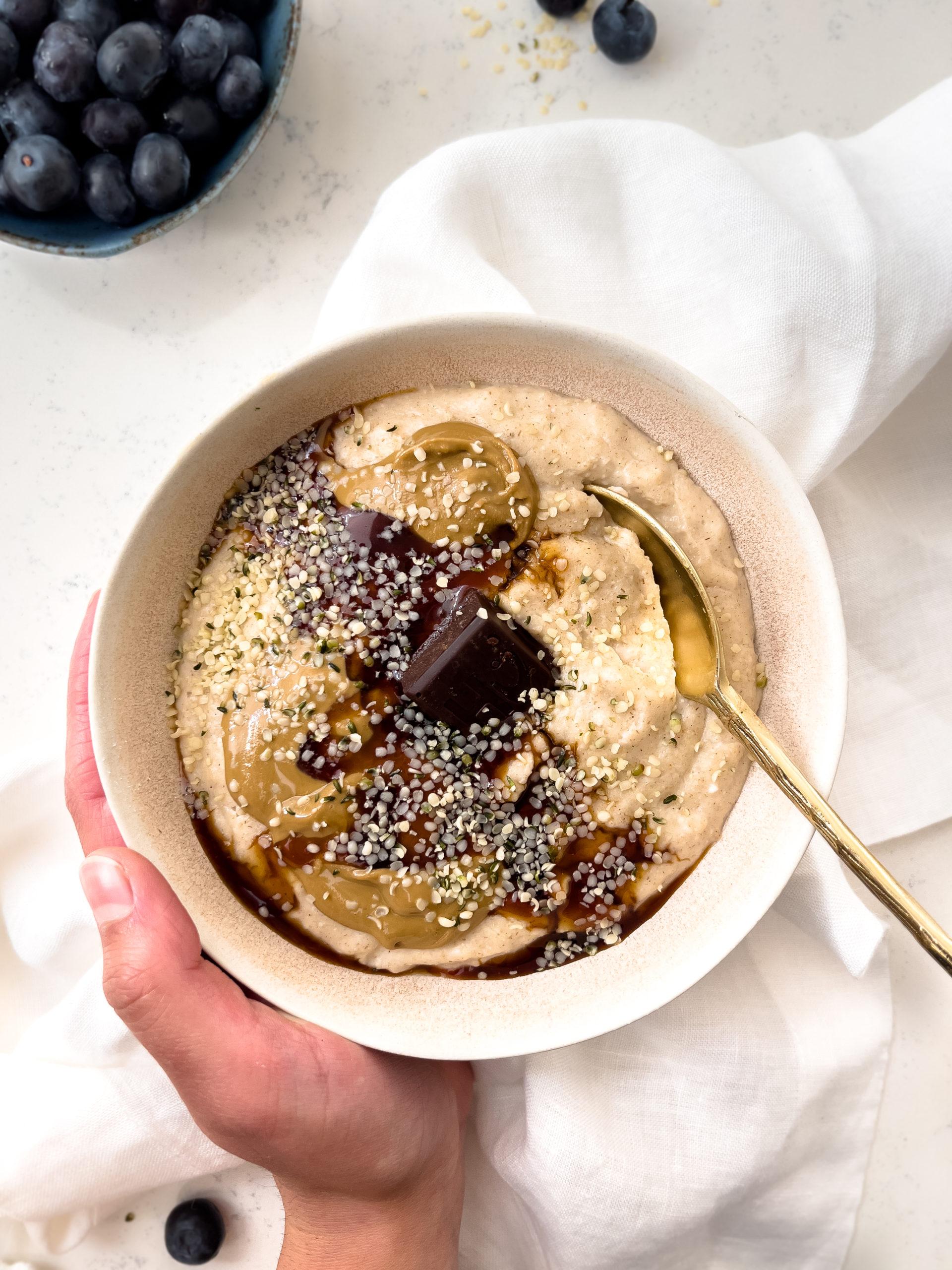 oatmeal in a bowl with a gold spoon next to blueberries