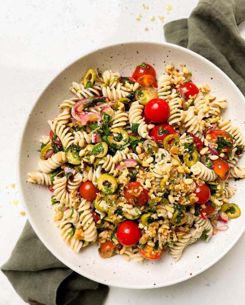 vegan pasta salad in a speckled bowl on a green linen cloth
