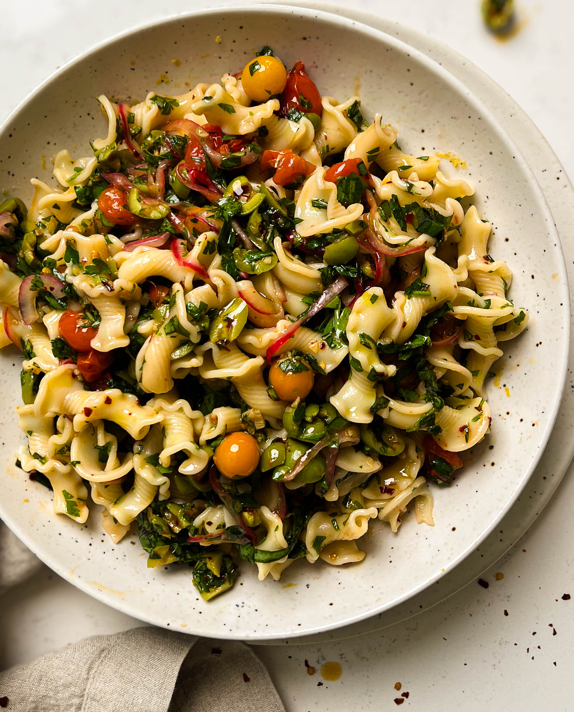 cherry tomato pasta salad in a speckled bowl