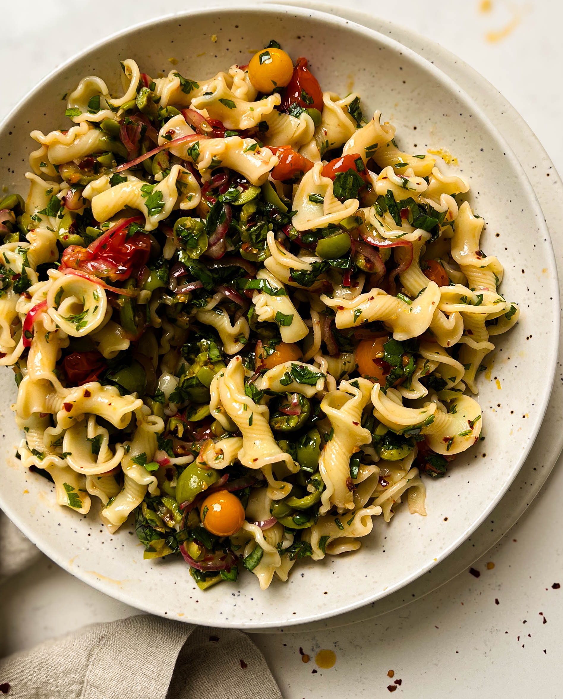 cherry tomato pasta salad in a speckled bowl