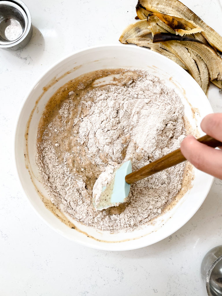 folding in flour into the banana bread wet ingredient mixture