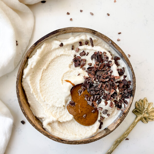 nice cream in a coconut bowl topped with granola and nut butter