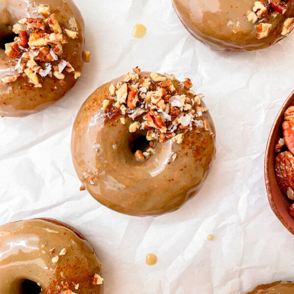 cinnamon glazed vegan baked pumpkin donuts with flaky salt and pecans on top