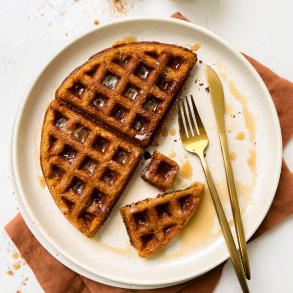 pumpkin waffle on a beige plate with gold flatware