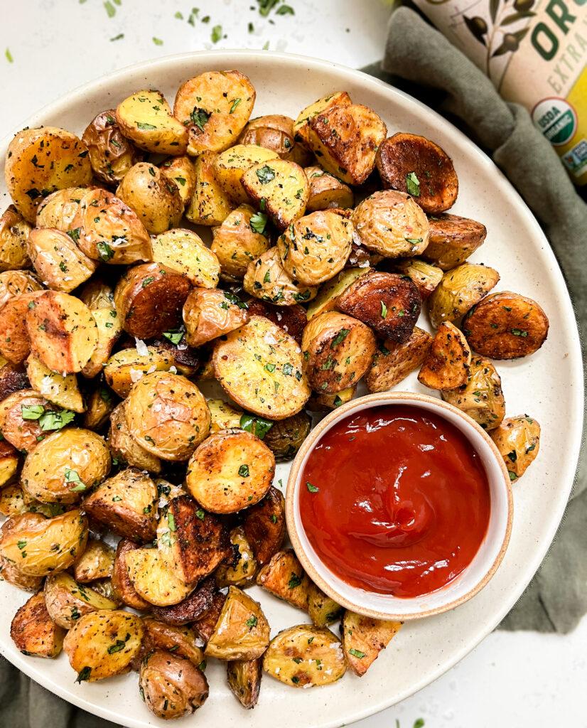 crispy oven baked potatoes on a beige plate next to a bowl of ketchup