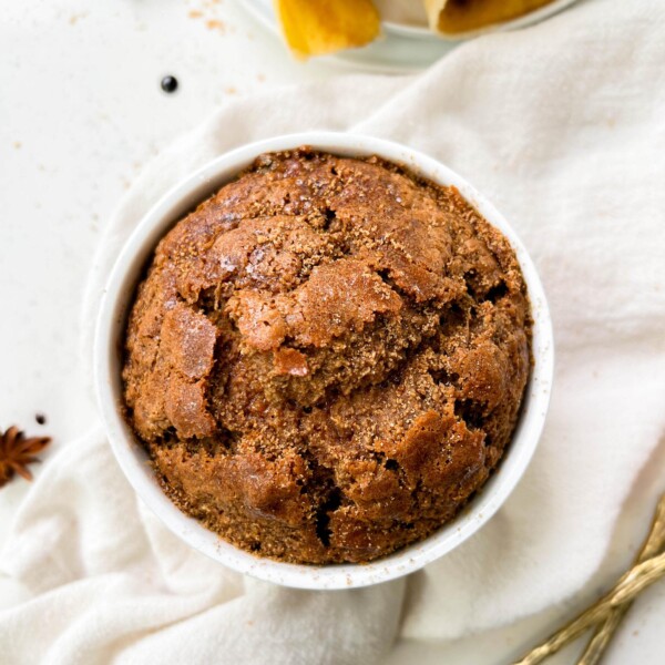 fluffy gingerbread baked oats in a ramekin next to banana peels and coconut sugar