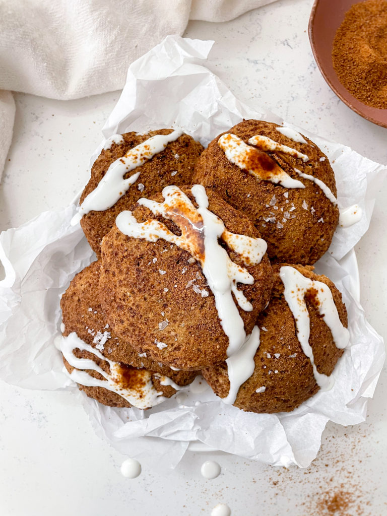 pumpkin glazed cookies in a bowl of parchment paper next to a linen 