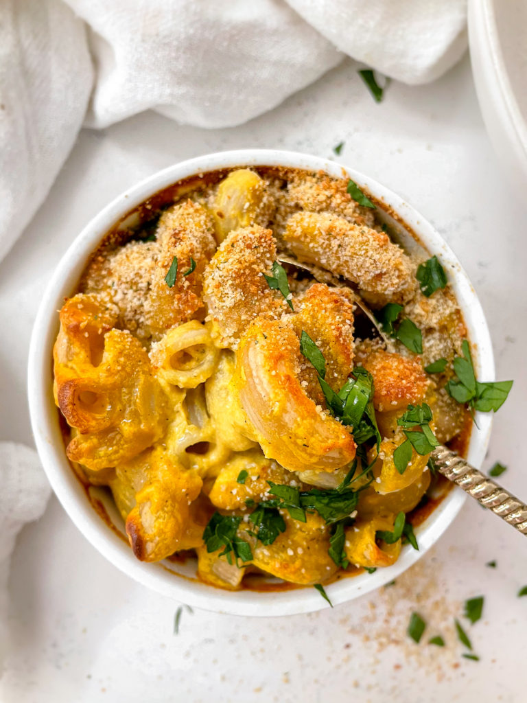 creamy vegan mac n' cheese with squash and breadcrumbs on top with a sprinkle of parsley