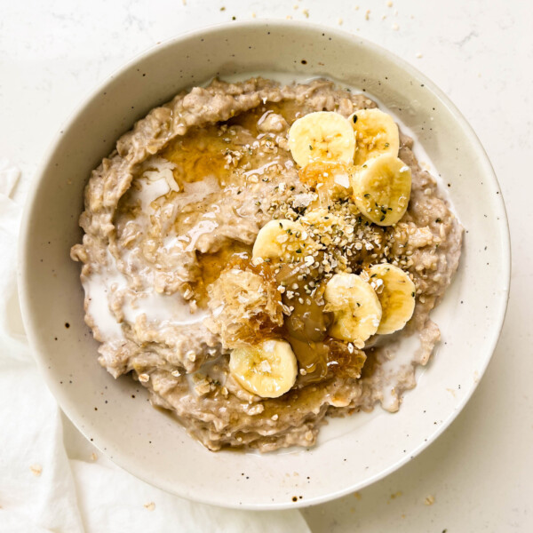 a bowl of the best creamy oatmeal with banana, honey and sunflower butter on top