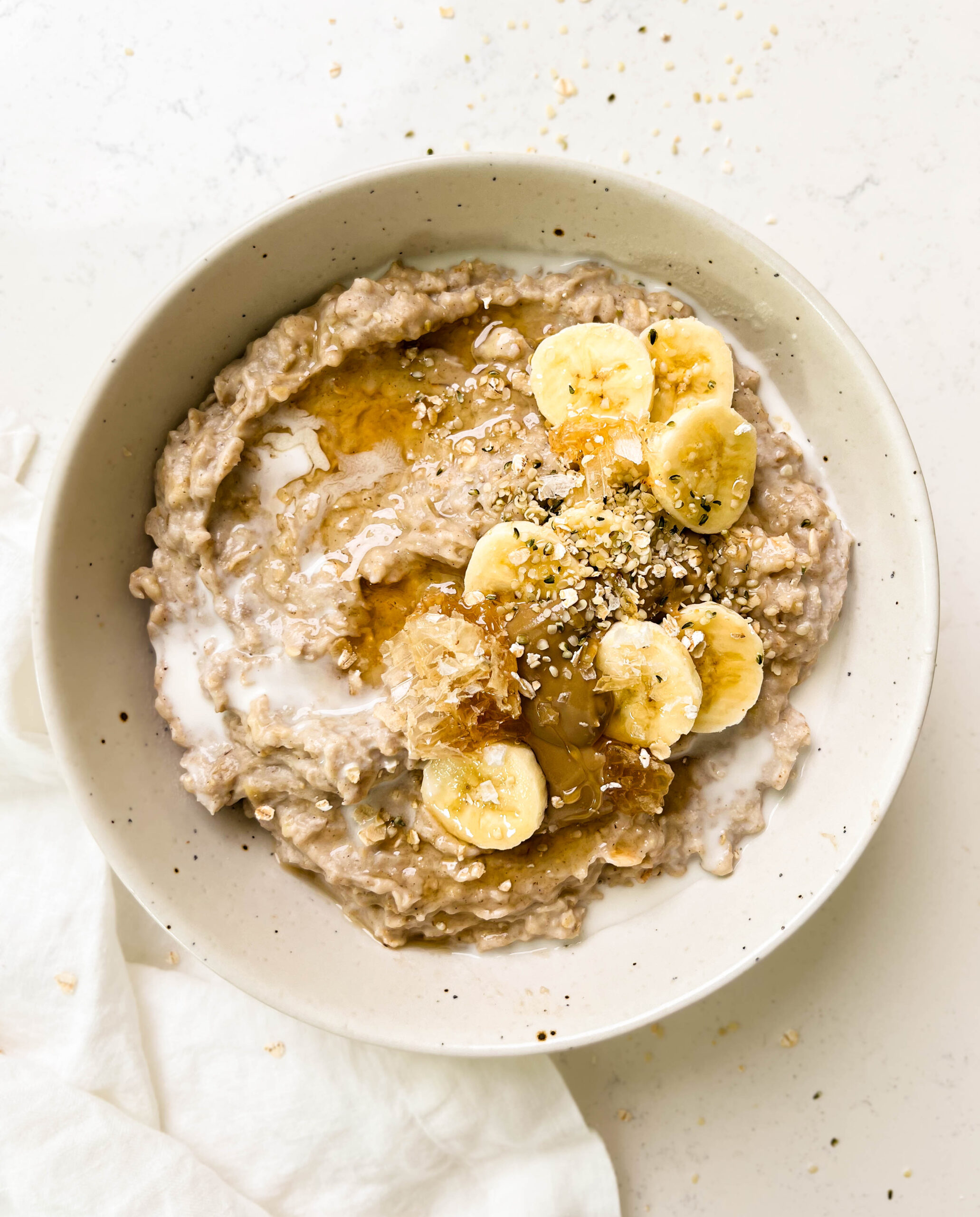 a bowl of the best creamy oatmeal with banana, honey and sunflower butter on top