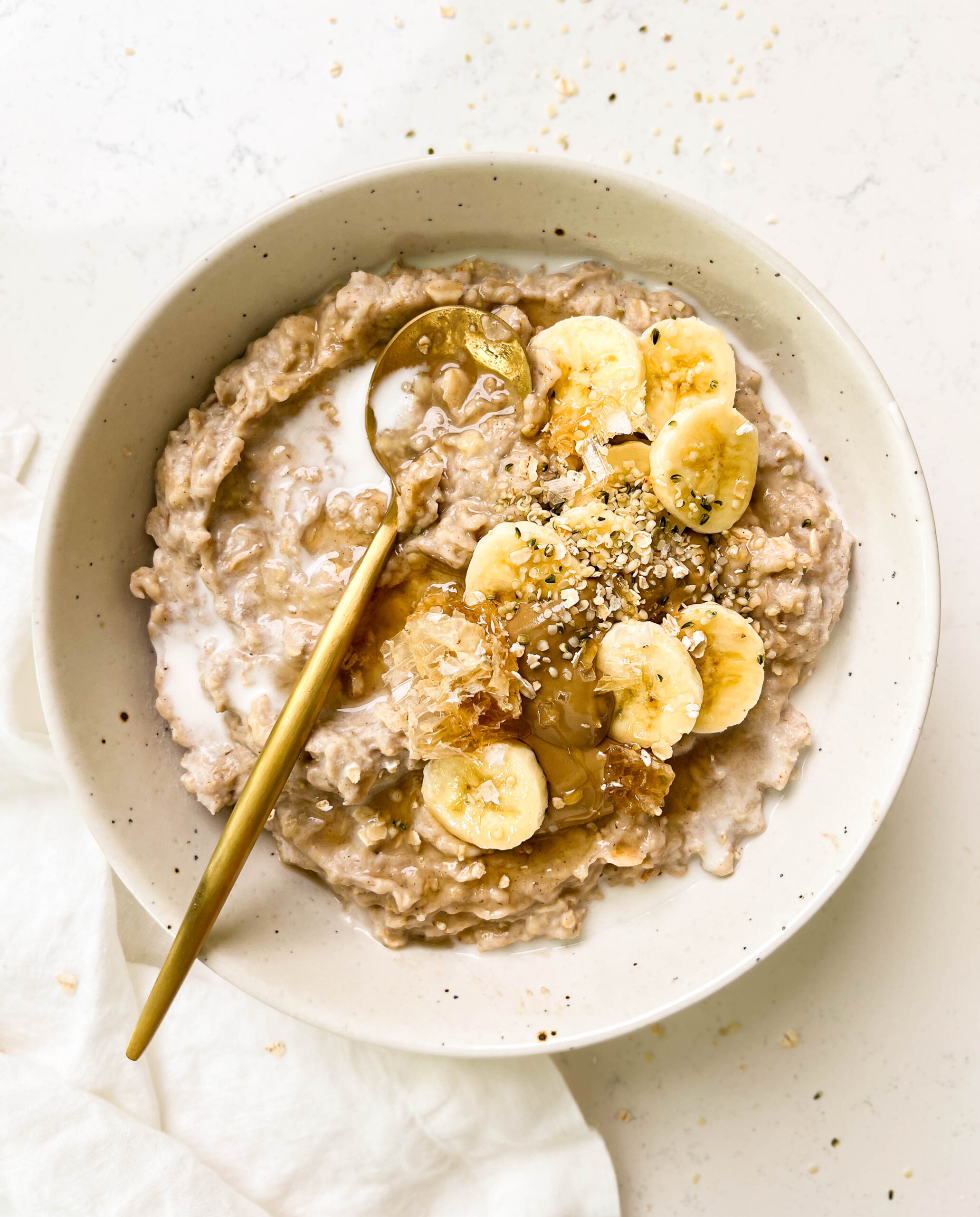 a bowl of the best creamy oatmeal with banana, honey and sunflower butter on top