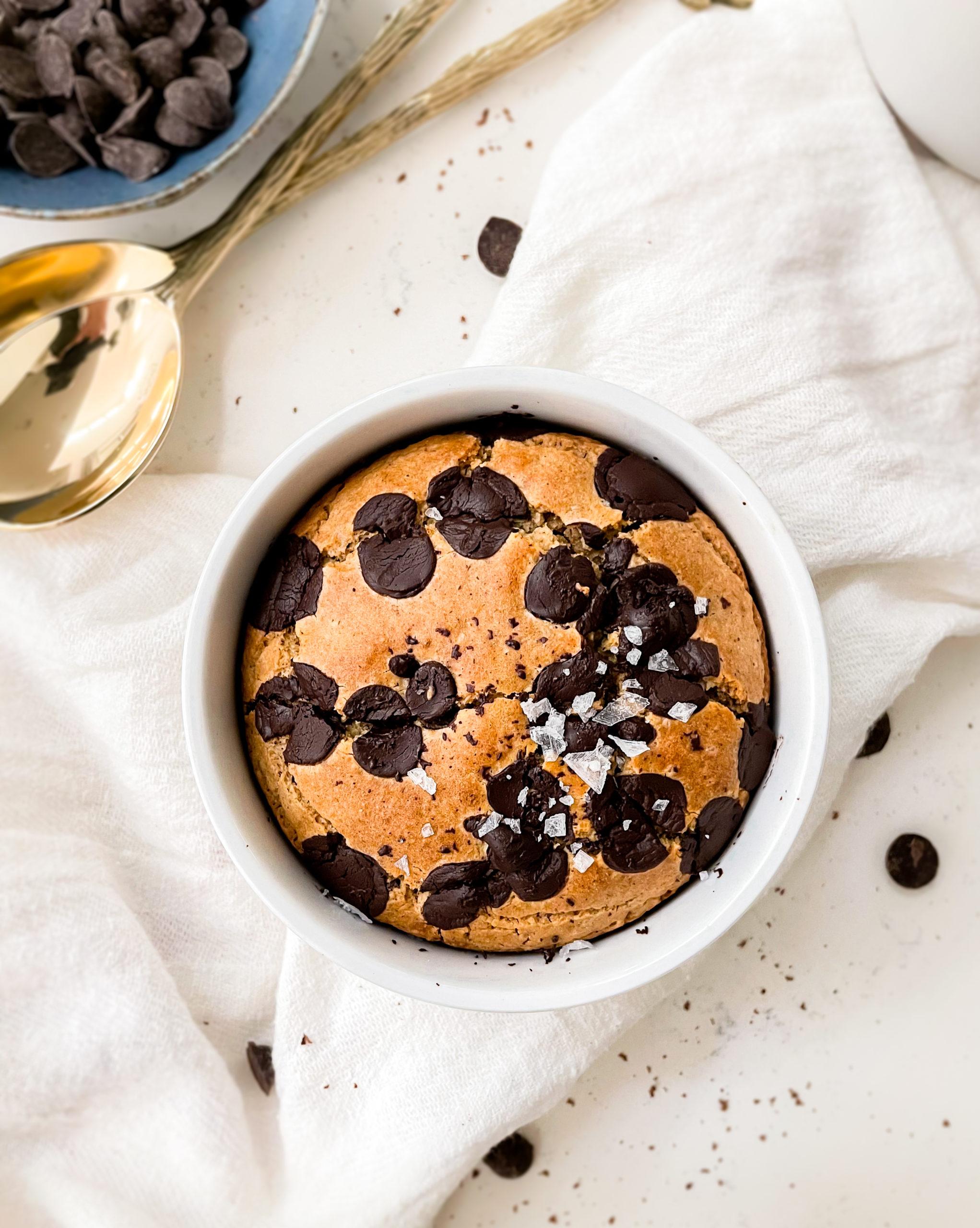 baked oats in a ramekin on a cloth next to a blue bowl