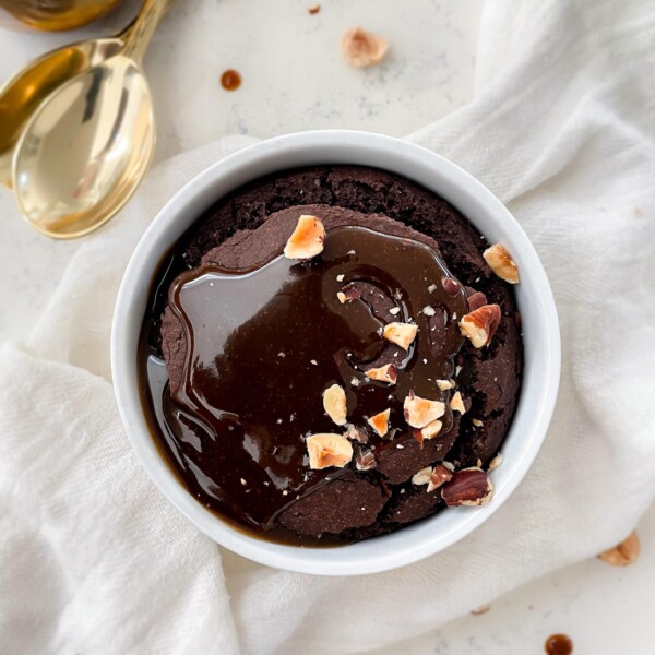 chocolate oats in a ramekin on top of a cloth napkin next to golds spoons and a jar