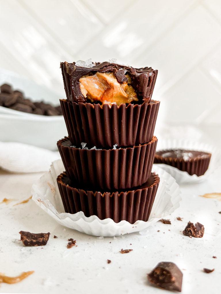 4 peanut butter cups stacked on top of one another next to a white bowl of chocolate