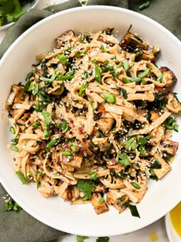 chili oil noodles in a white bowl on a green napkin