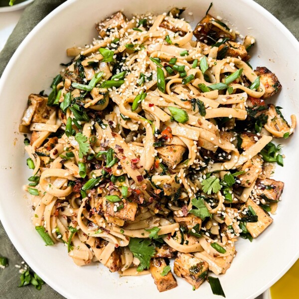 chili oil noodles in a white bowl on a green napkin