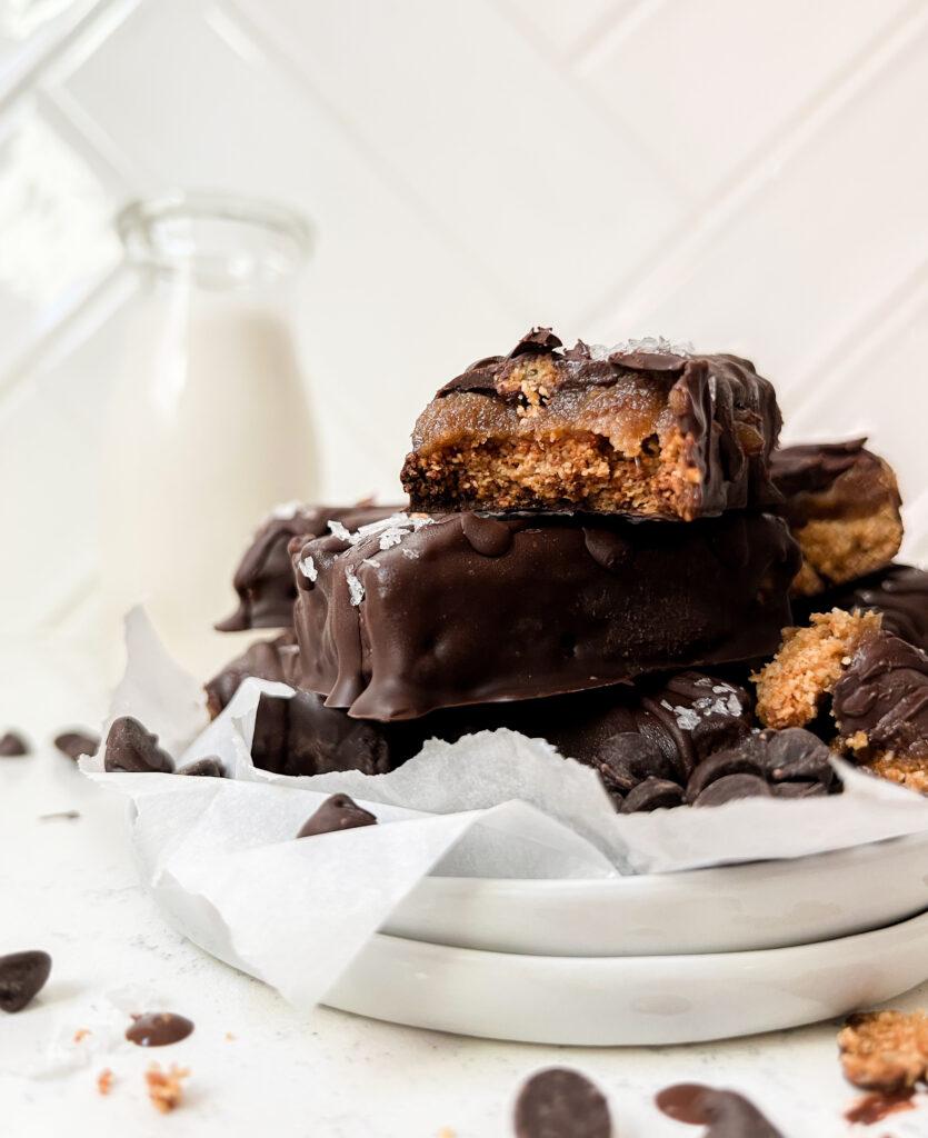 homemade vegan Twix bars on parchment paper next to a bowl of flaky salt
