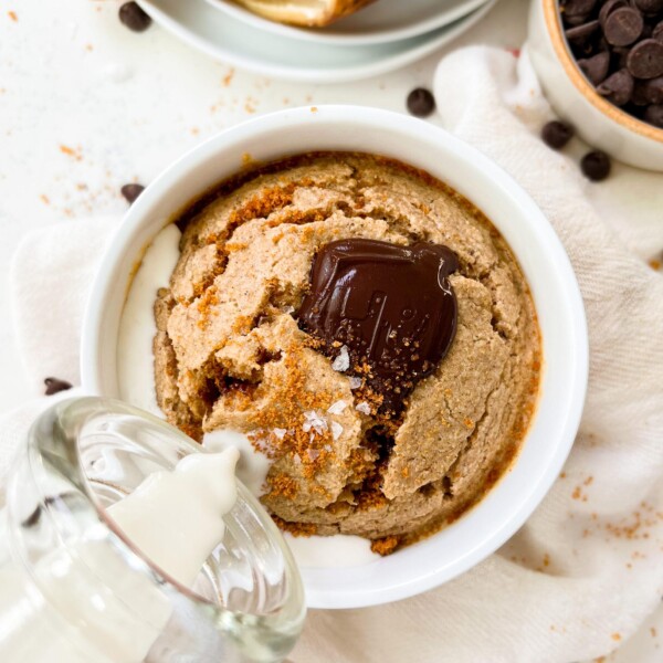 vegan banana bread baked oats in a white ramekin next to a banana peel and chocolate chips