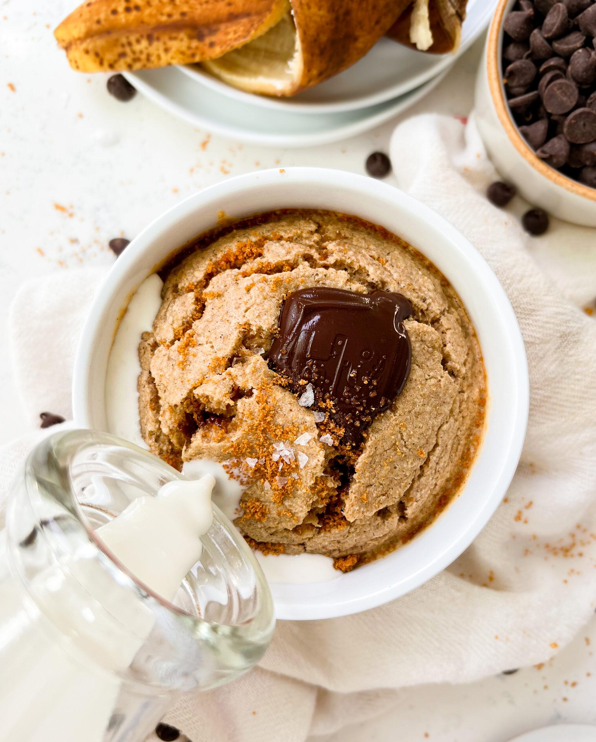 vegan banana bread baked oats in a white ramekin next to a banana peel and chocolate chips