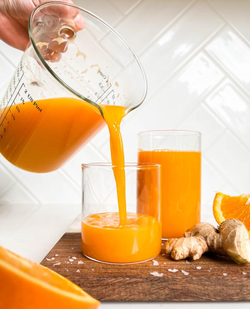 immune boosting juice pouring into cups on a wooden cutting board