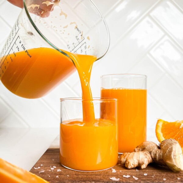 immune boosting juice pouring into cups on a wooden cutting board