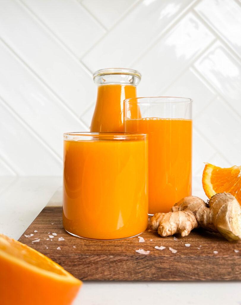 immune boosting juice in a glass jar and glass next on a wooden cutting board