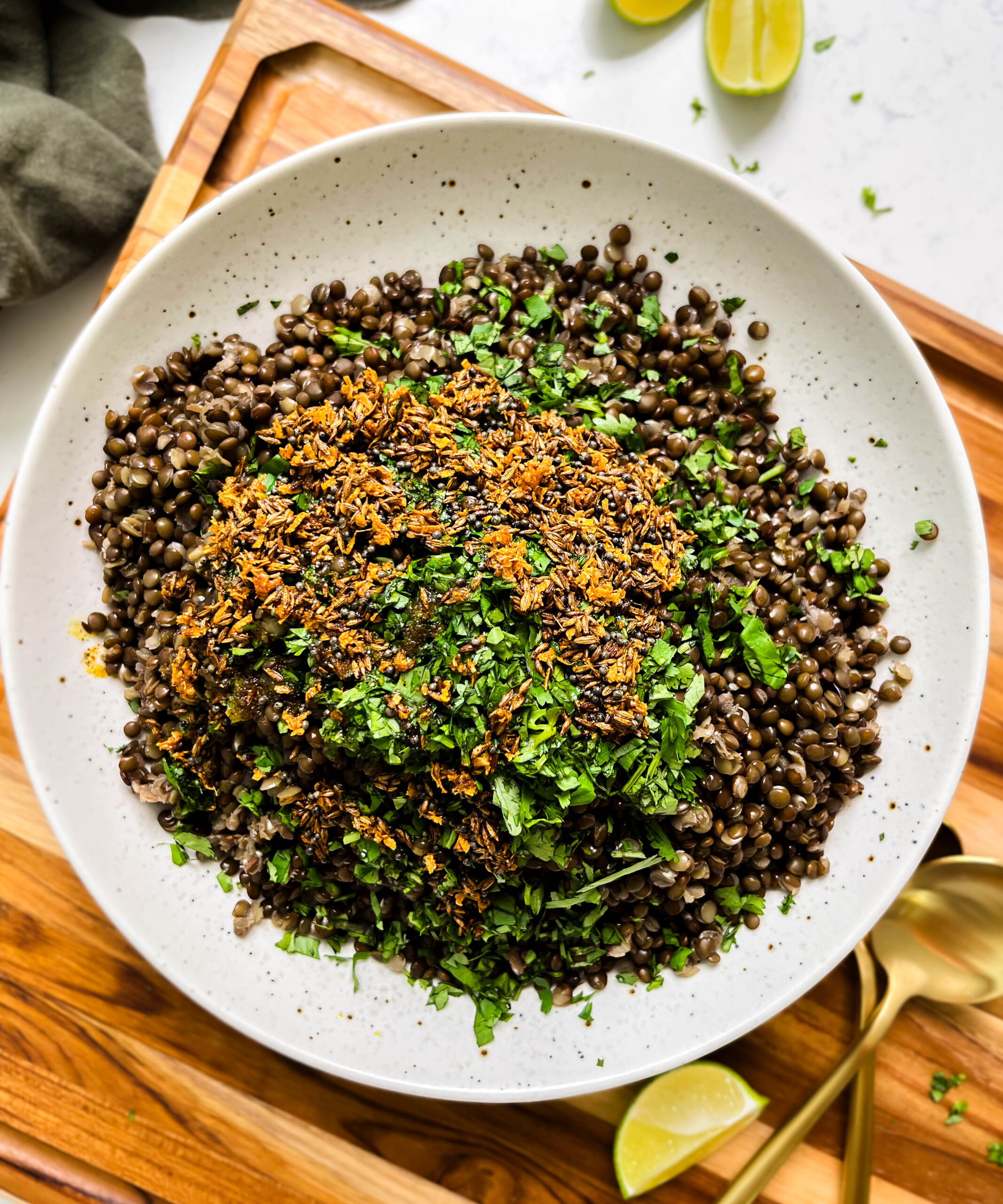 spicy black lentils in a white bowl next to lime wedges