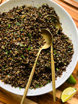 spicy black lentils in a white bowl next to lime wedges