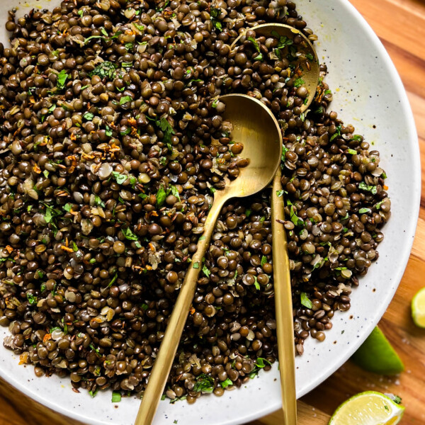 spicy black lentils in a white bowl next to lime wedges