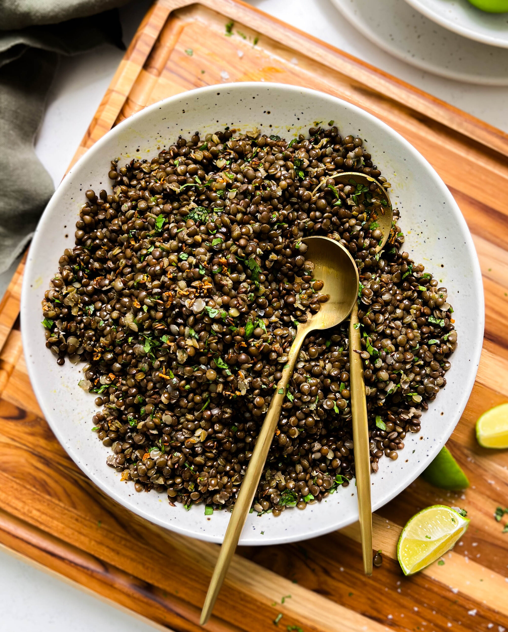spicy black lentils in a white bowl next to lime wedges