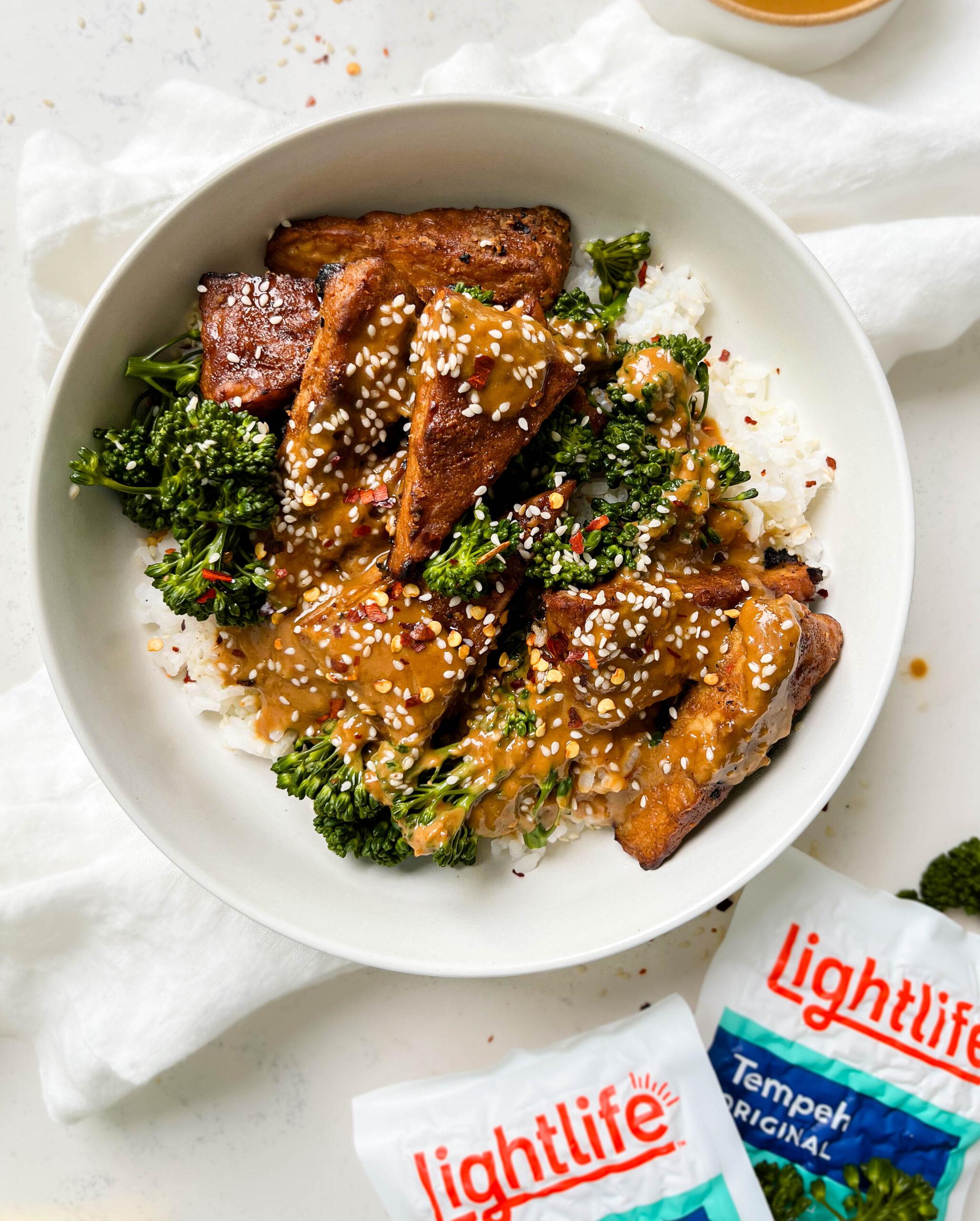 marinated peanut tempeh with white rice and broccoli next to a white linen cloth