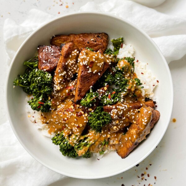 marinated peanut tempeh with white rice and broccoli next to a white linen cloth