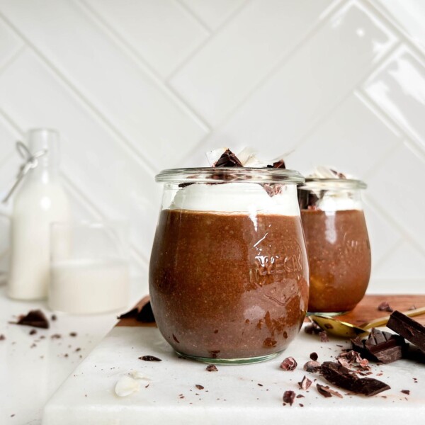 healthy chocolate seed pudding in a jar on a white cutting board next to chocolate and jar of milk