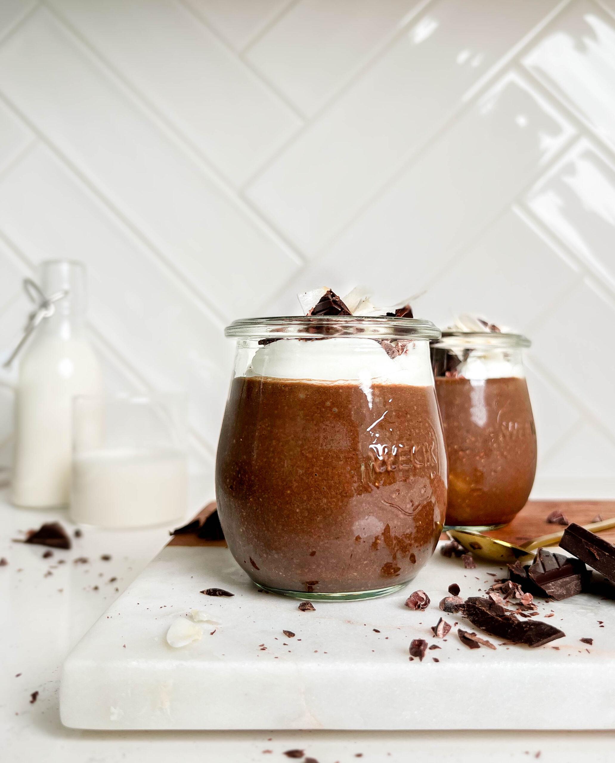 healthy chocolate seed pudding in a jar on a white cutting board next to chocolate and jar of milk