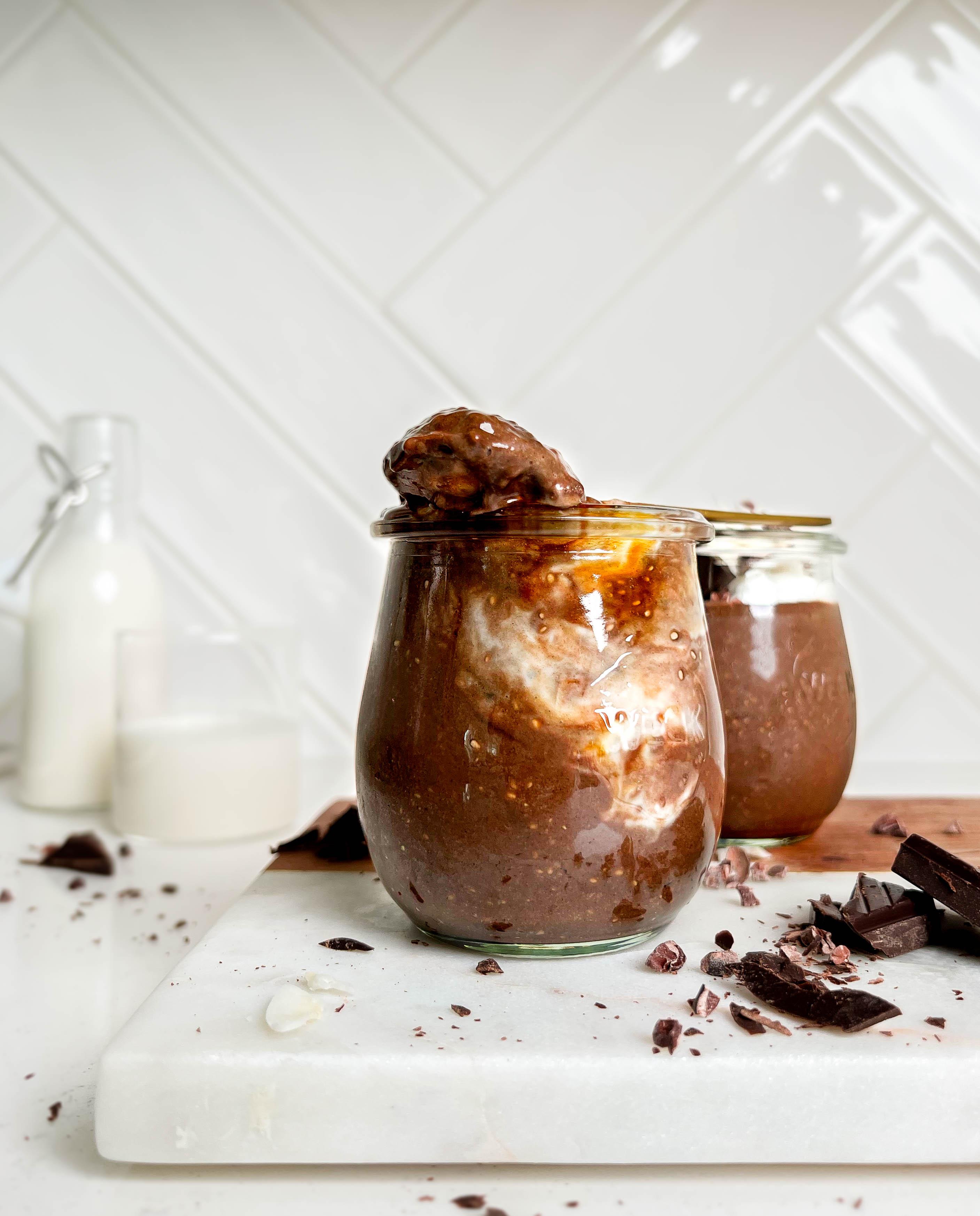 healthy chocolate seed pudding in a jar on a white cutting board next to chocolate and jar of milk