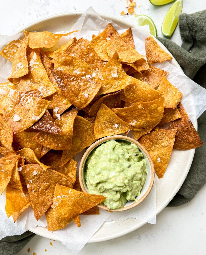crispy homemade baked tortilla chips next to avocado crema and limes