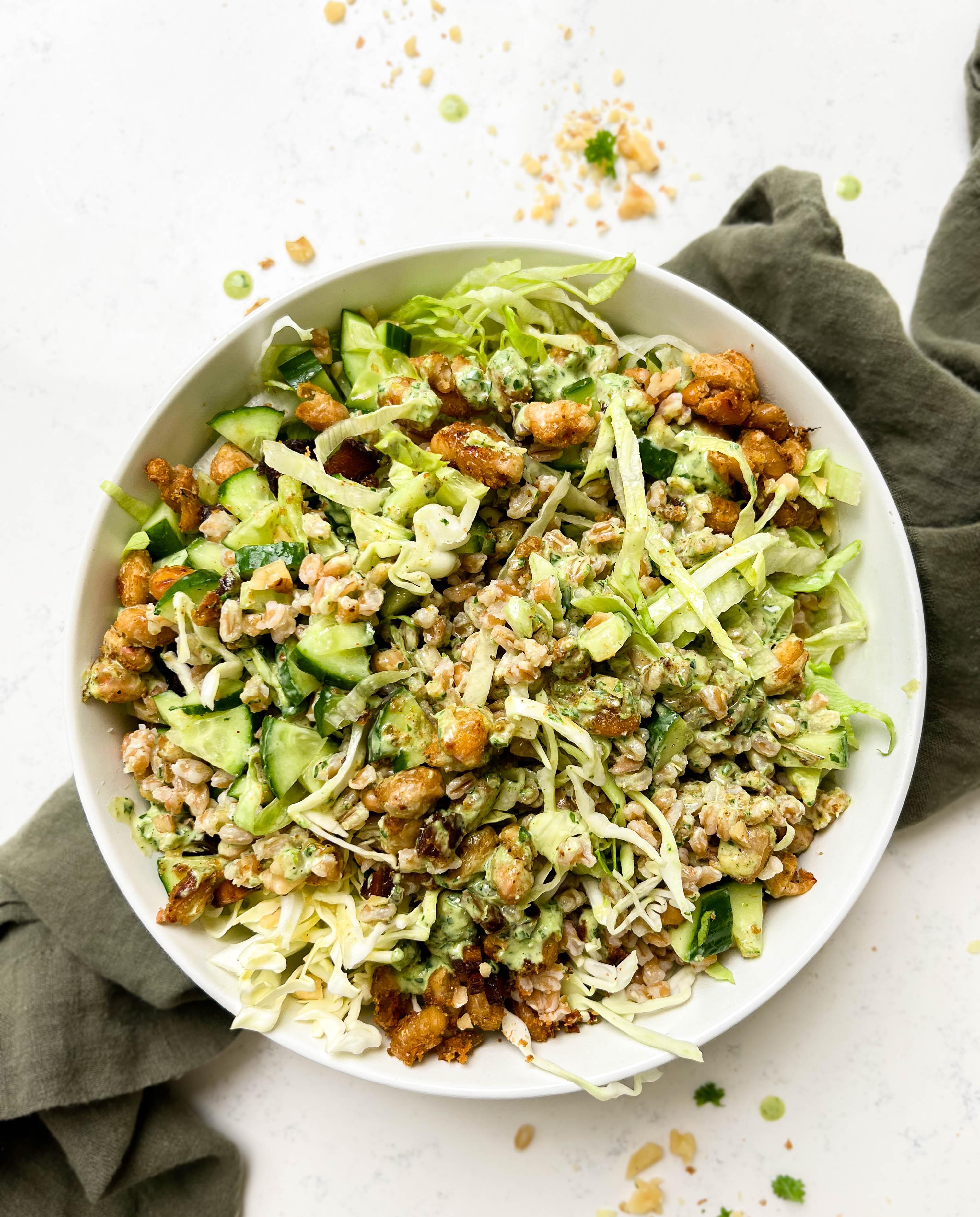 crunchy green cabbage salad with beans and farro next to parsley tahini dressing